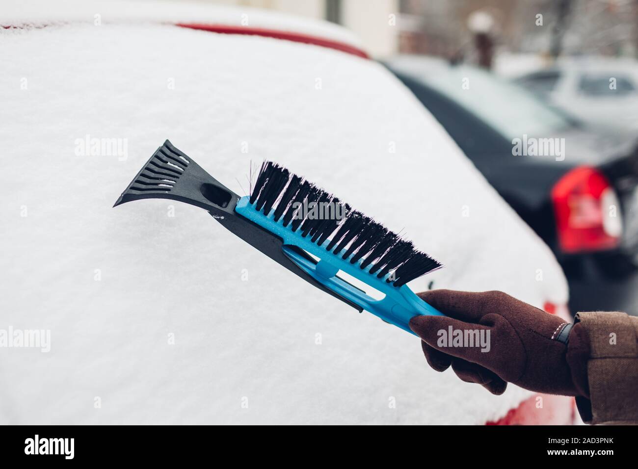 Car cleaning from snow using broom. Man taking care of automobile