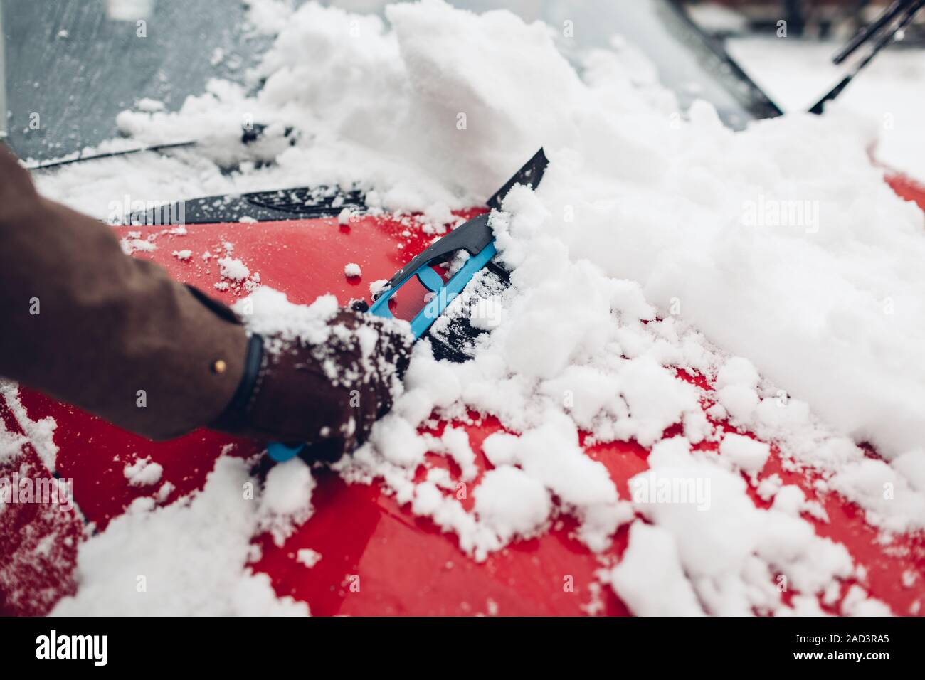 Car cleaning from snow using broom. Man taking care of automobile