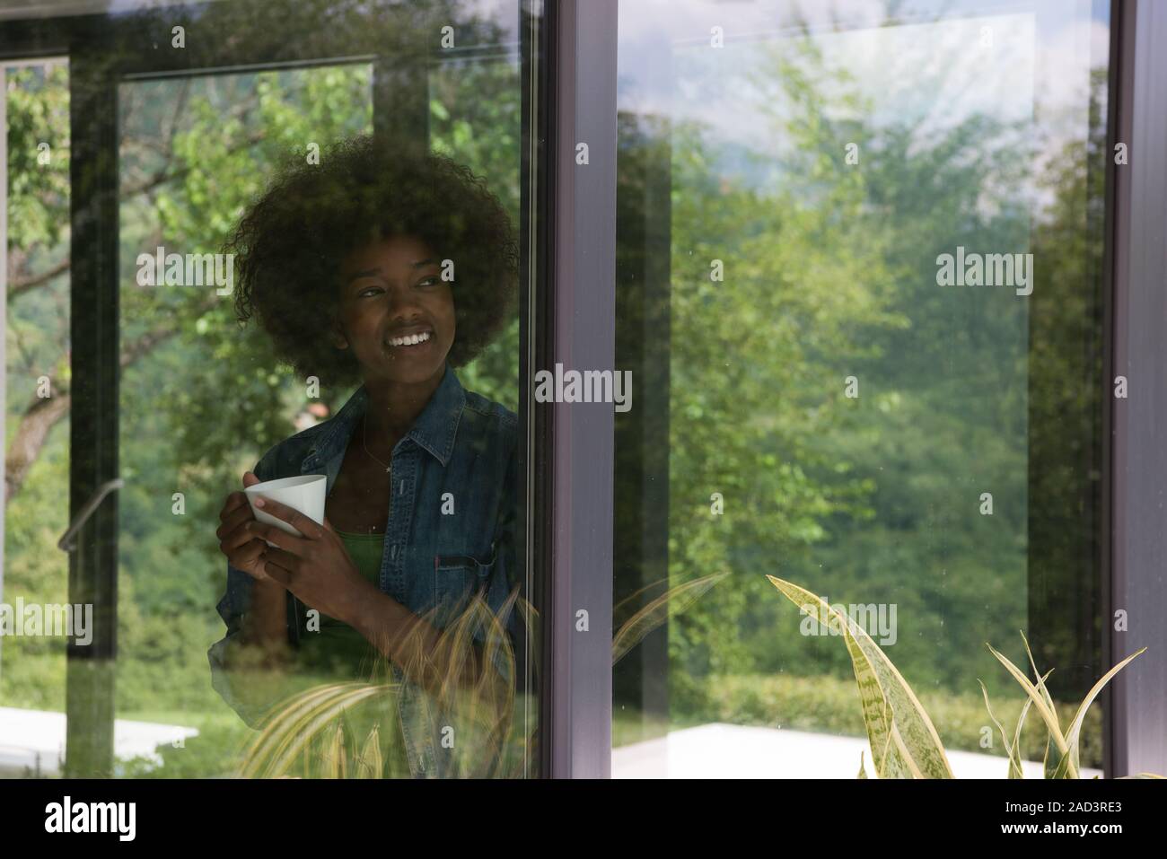 African American woman drinking coffee looking out the window Stock ...
