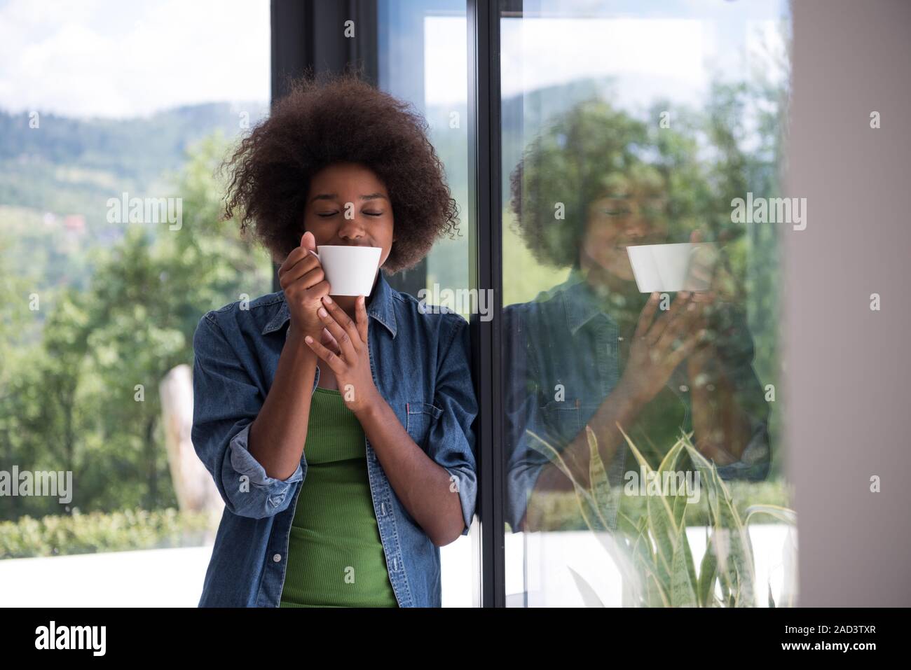 African American woman drinking coffee looking out the window Stock ...