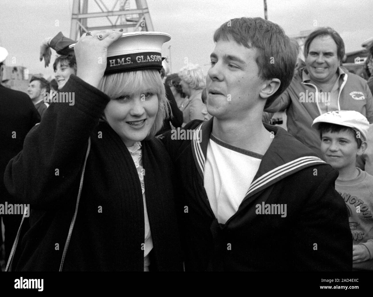 AJAXNETPHOTO. 19TH JUNE, 1982 - PORTSMOUTH, ENGLAND. - FALKLANDS VETERAN - A SAILOR OF THE SHEFFIELD CLASS (TYPE 42/1&2) DESTROYER HMS GLASGOW LOSES HIS HAT TO A PRETTY YOUNG RELATIVE WHEN HIS BOMB DAMAGED SHIP RETURNED TO PORTSMOUTH IN 1982.  PHOTO:JONATHAN EASTLAND/AJAX.  REF:HD NA GLAS 82 16. Stock Photo