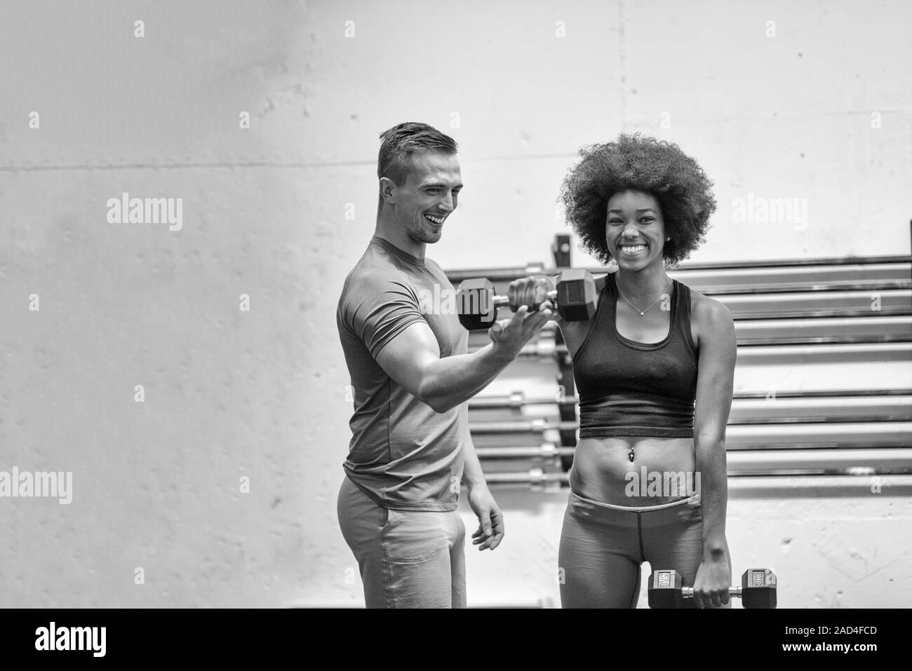 black woman doing bicep curls with fitness trainer Stock Photo