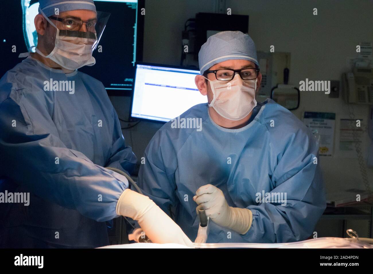 Appendix removal surgery. Surgeon teaching a surgical resident to use a laparoscopic stapler