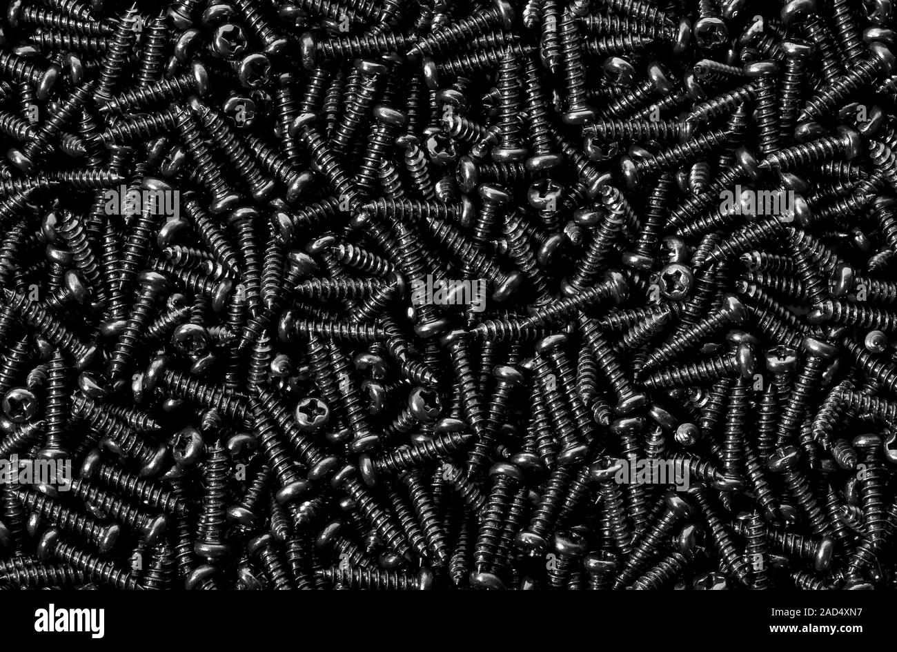 Background pile of shiny black screws Stock Photo