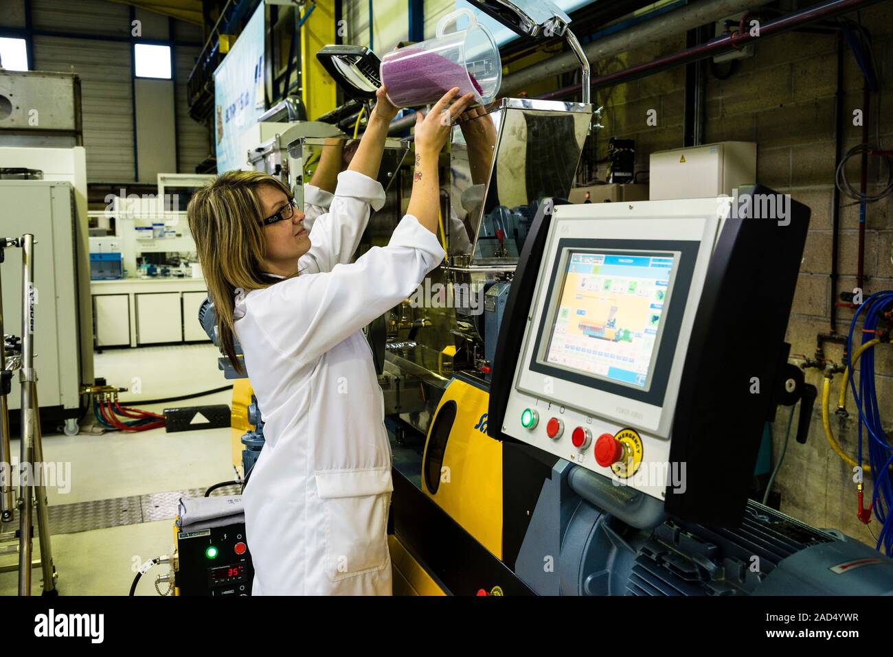 Plastics recycling. A technician pours recycled plastic granules into