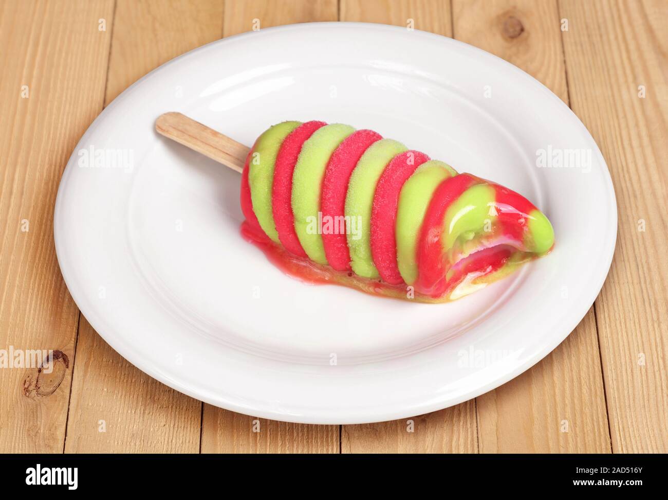 Melted colorful fruit ice cream in plate on wooden background Stock Photo