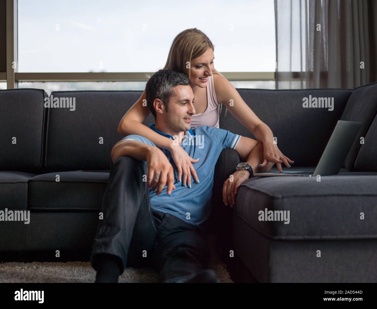 Attractive Couple Using A Laptop on couch Stock Photo - Alamy