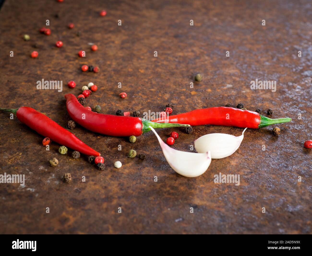 red hot chili pepper pods and peas, garlic clove on dark rusty metal background, side view