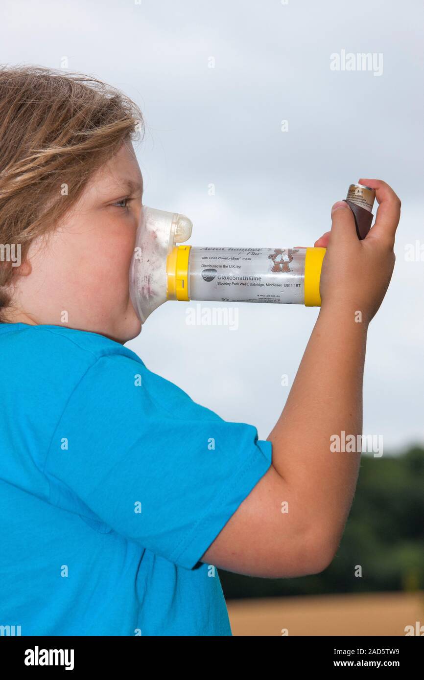 Eight year old boy using an inhaler with an aerochamber spacer to treat