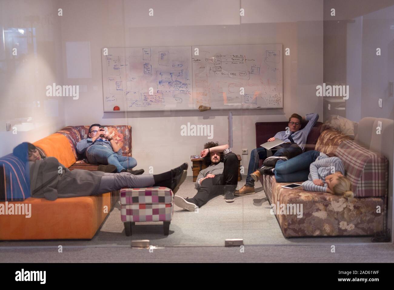 software developers sleeping on sofa in creative startup office Stock Photo