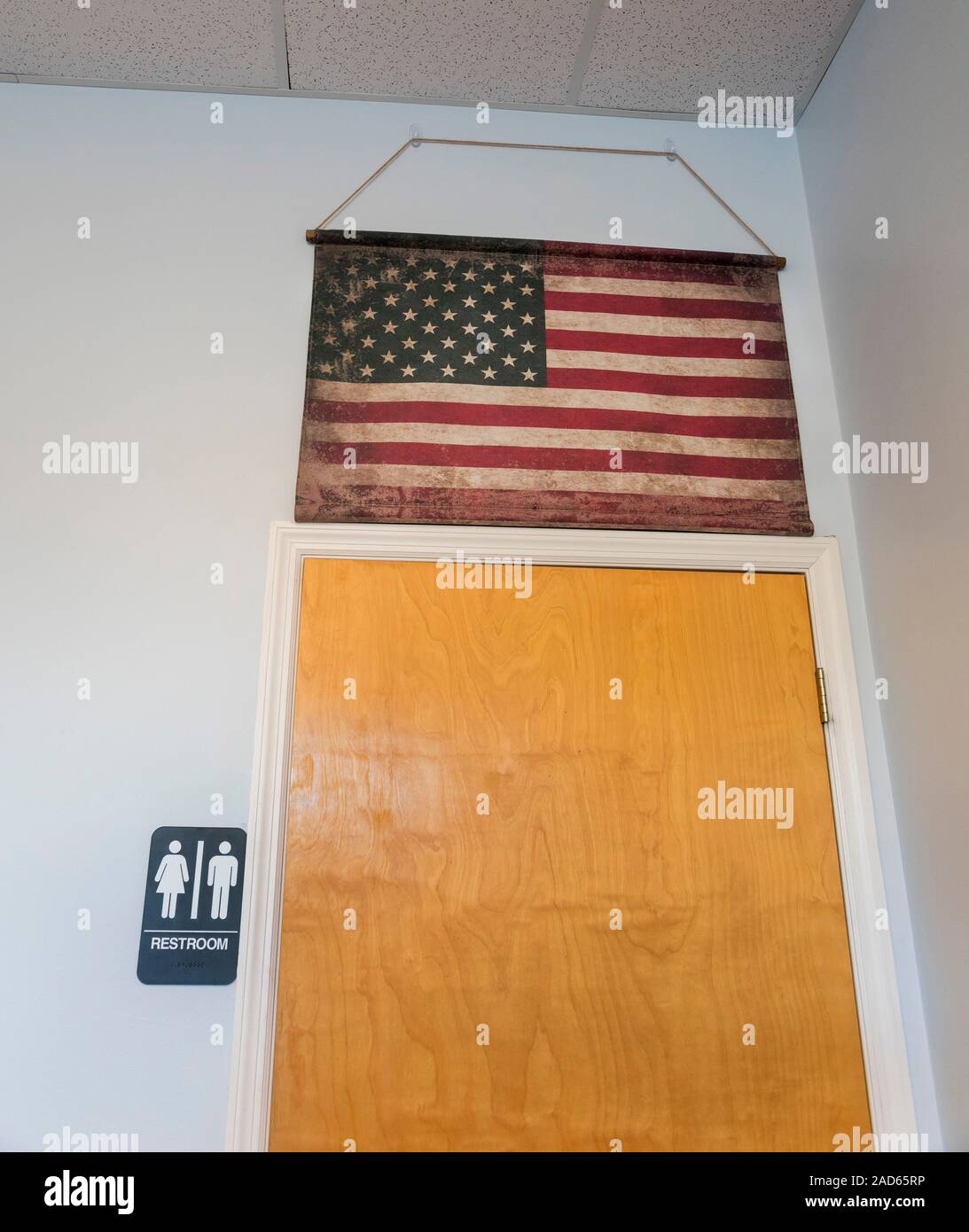 Old American Flag posted over the bathroom door of a business. Stock Photo