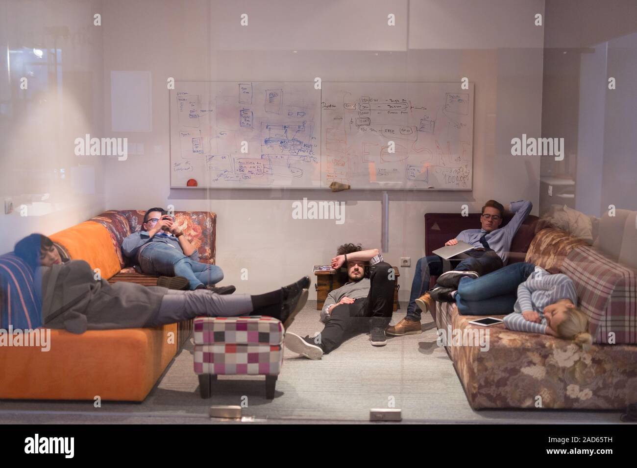 software developers sleeping on sofa in creative startup office Stock Photo