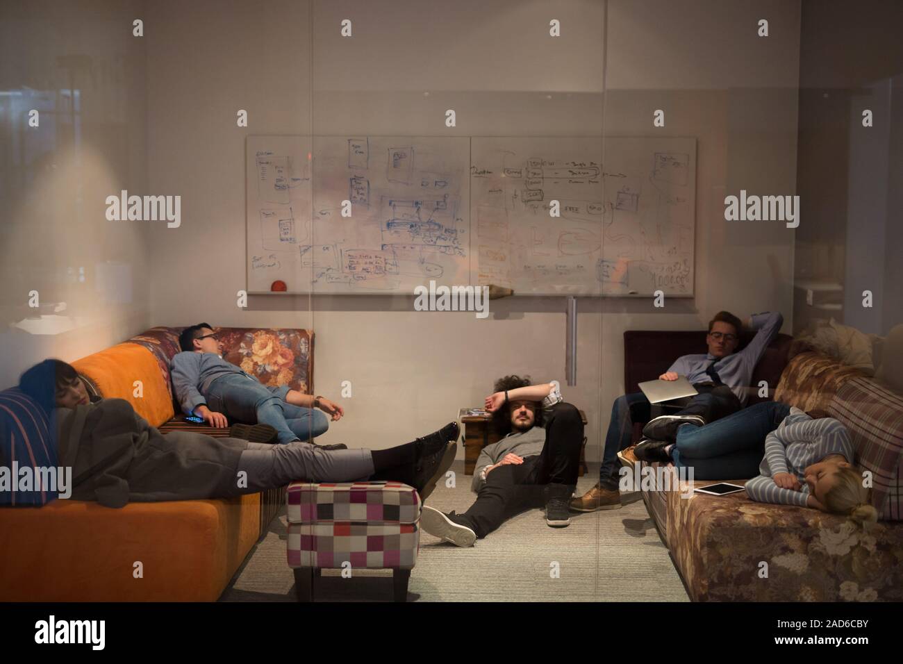 software developers sleeping on sofa in creative startup office Stock Photo