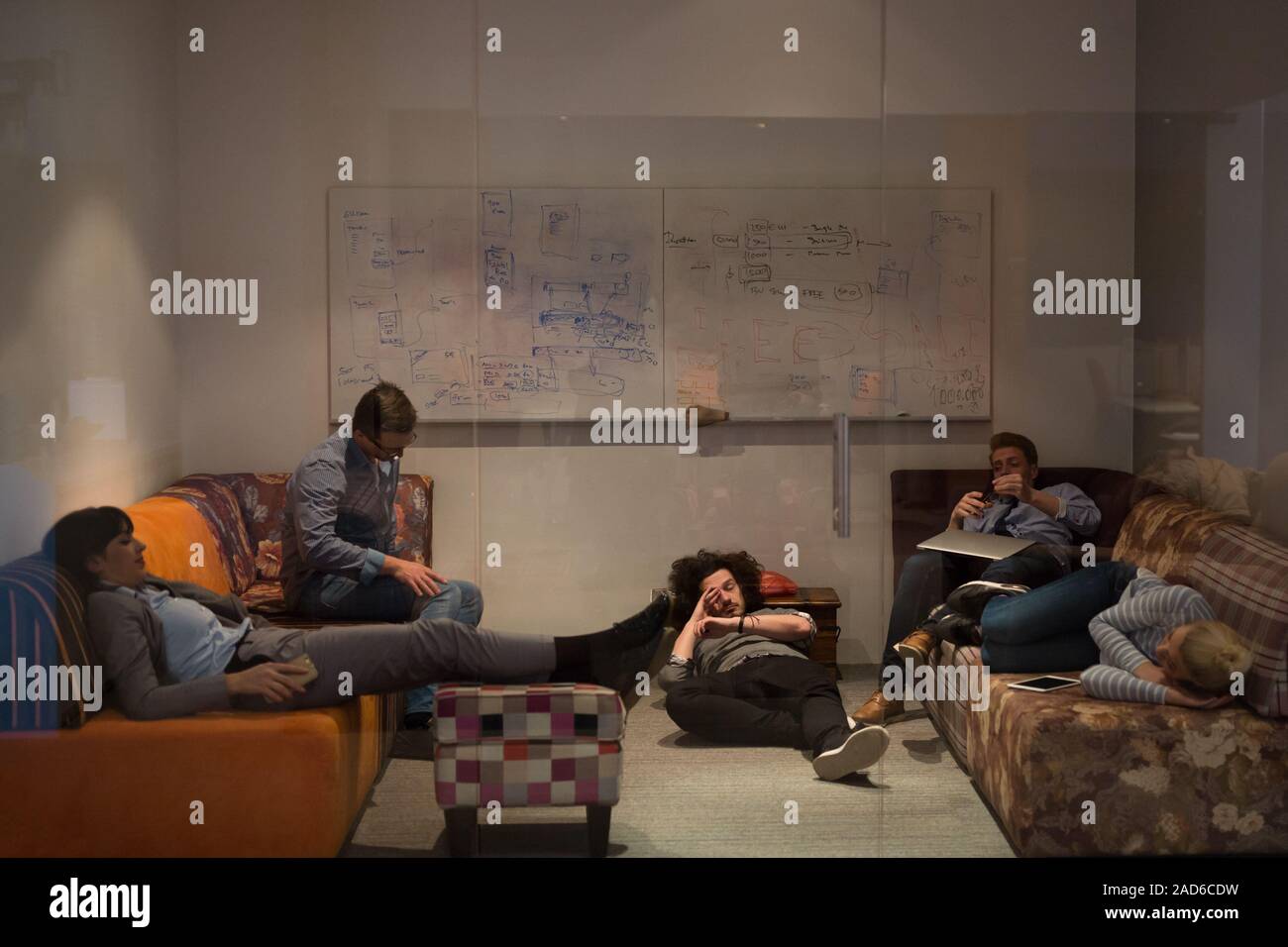 software developers sleeping on sofa in creative startup office Stock Photo
