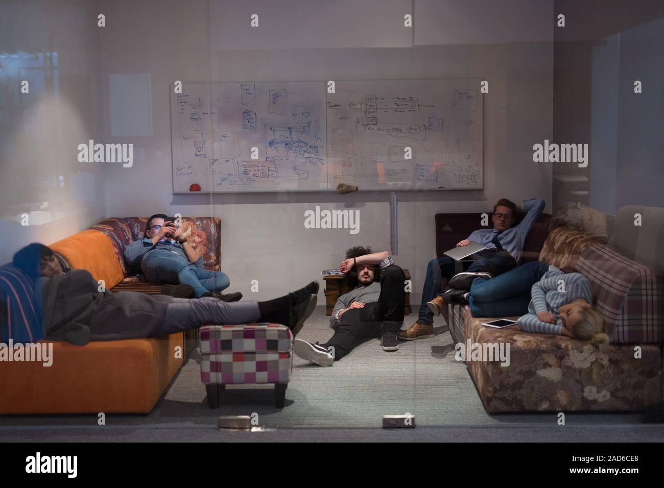 software developers sleeping on sofa in creative startup office Stock Photo
