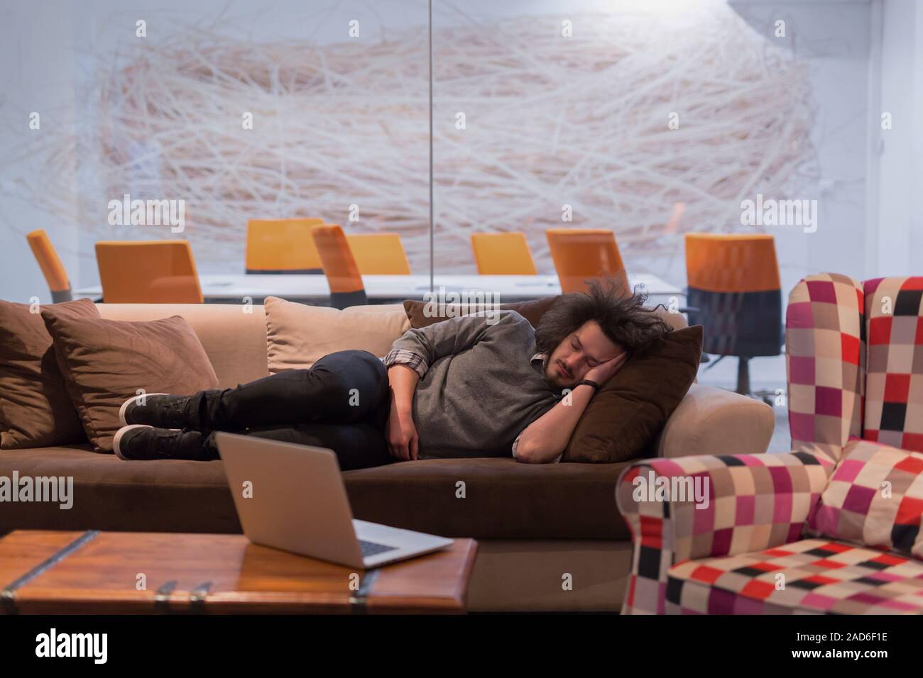 man sleeping on a sofa  in a creative office Stock Photo