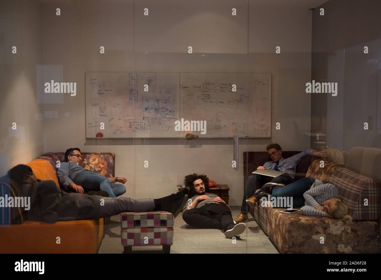 software developers sleeping on sofa in creative startup office Stock Photo