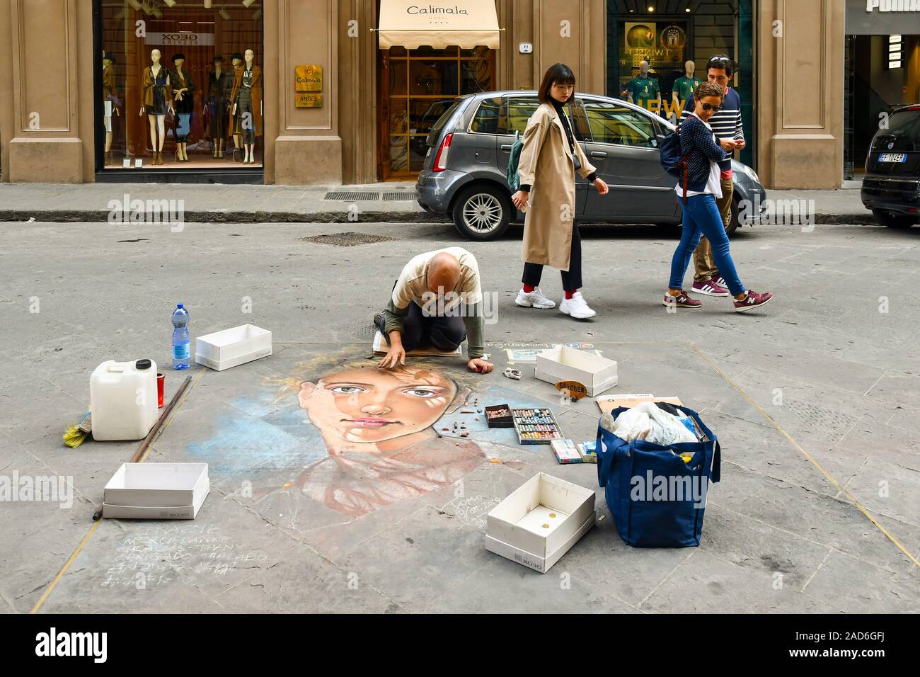 Japanese pavement artist Tomoteru Saito drawing with colored chalk on the ground of Via Calimala in the historic centre of Florence, Tuscany, Italy Stock Photo