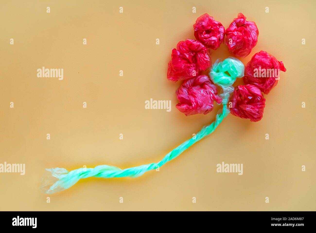 Flower made of rolled colorful plastic bags. Recycling and waste reducing concept. Top view. Stock Photo