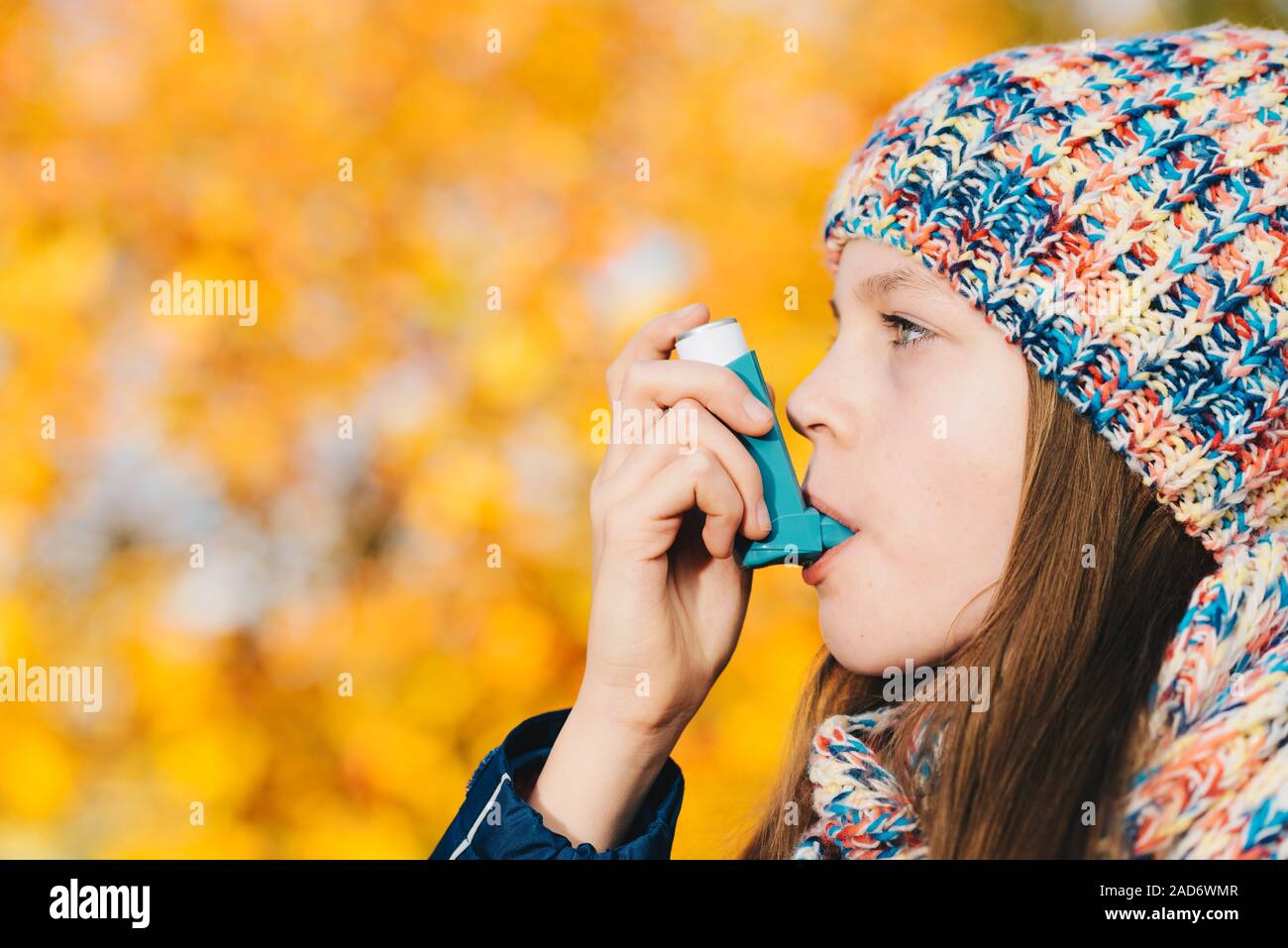 Asthma patient girl inhaling medication for treating shortness of breath and wheezing in a park Stock Photo