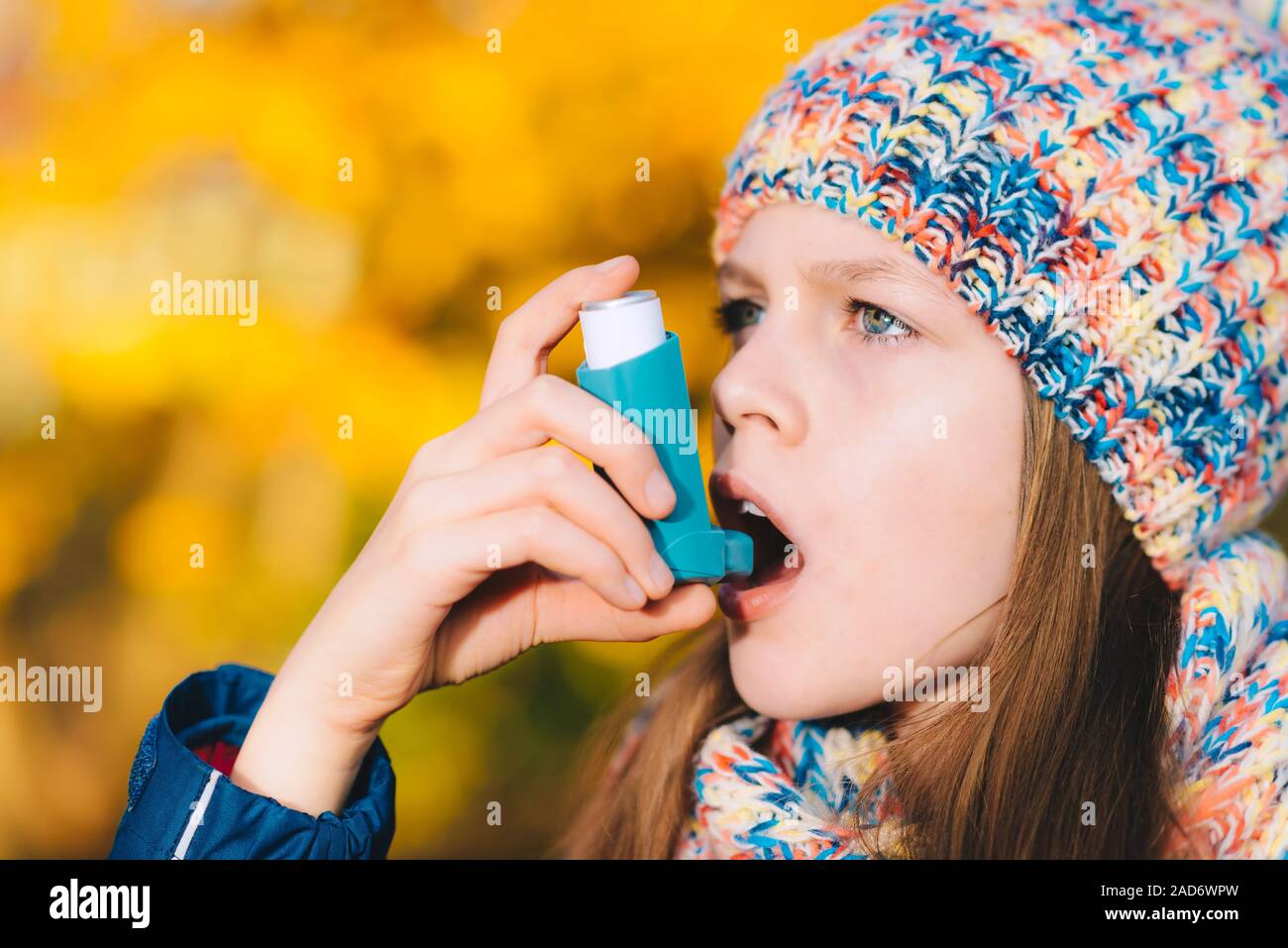 Asthma patient girl inhaling medication for treating shortness of breath and wheezing in a park Stock Photo