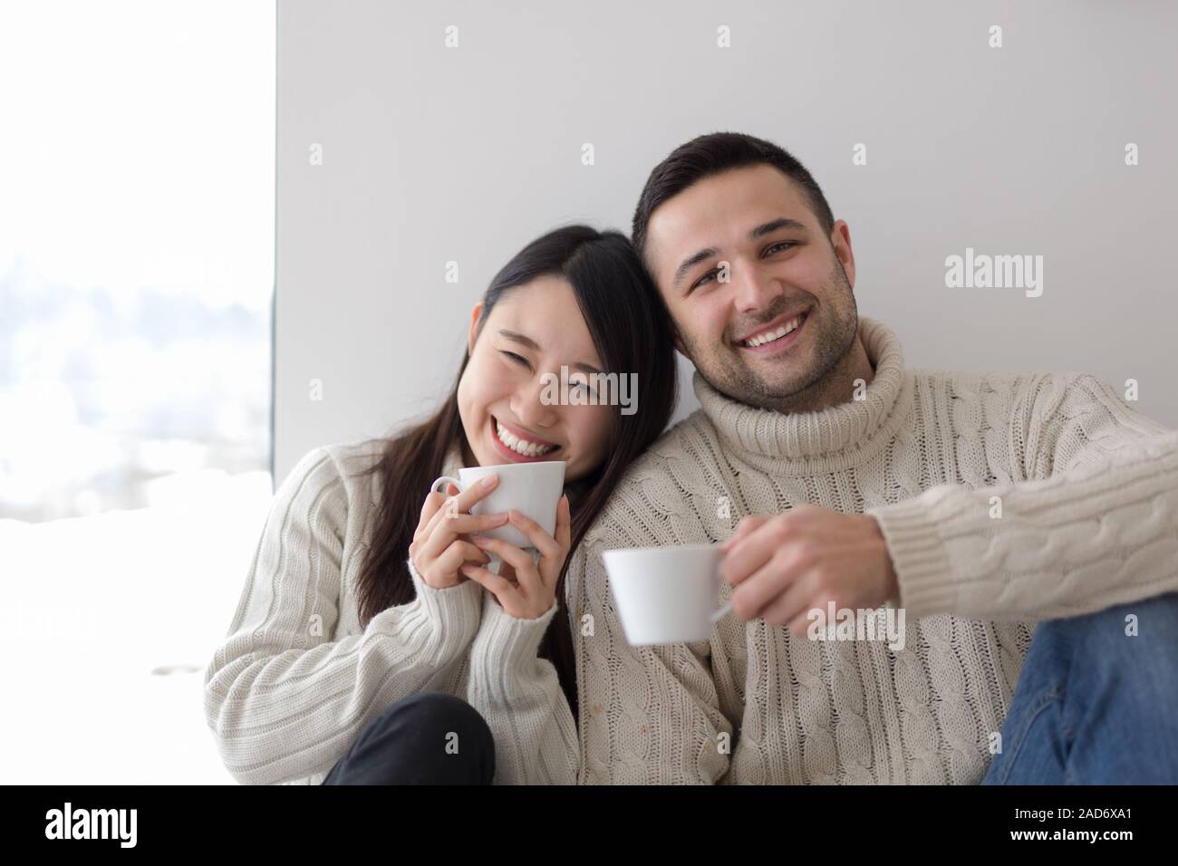 multiethnic couple enjoying morning coffee by the window Stock Photo
