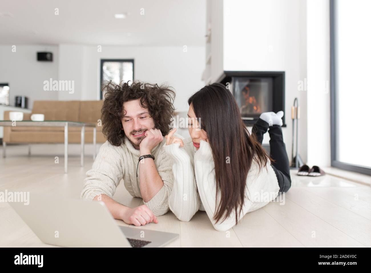 young multiethnic couple using a laptop on the floor Stock Photo