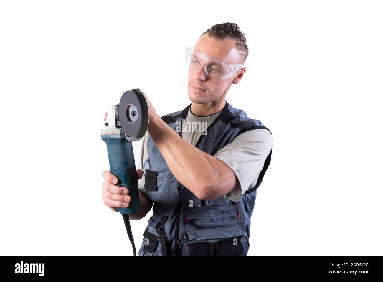 The builder in goggles, with an angle grinder in his hands. Stock Photo