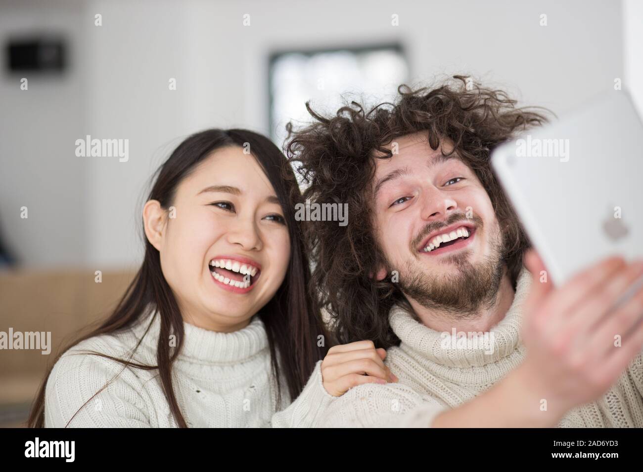 multiethnic couple using tablet computer in front of fireplace Stock Photo