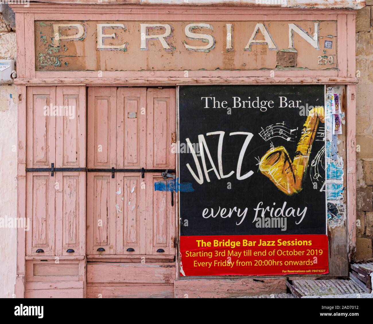 Disused Persian Cafe on the dockside of the Grand Harbour in Valletta, Malta. Recent poster advertising Jazz at the Bridge Bar. Stock Photo