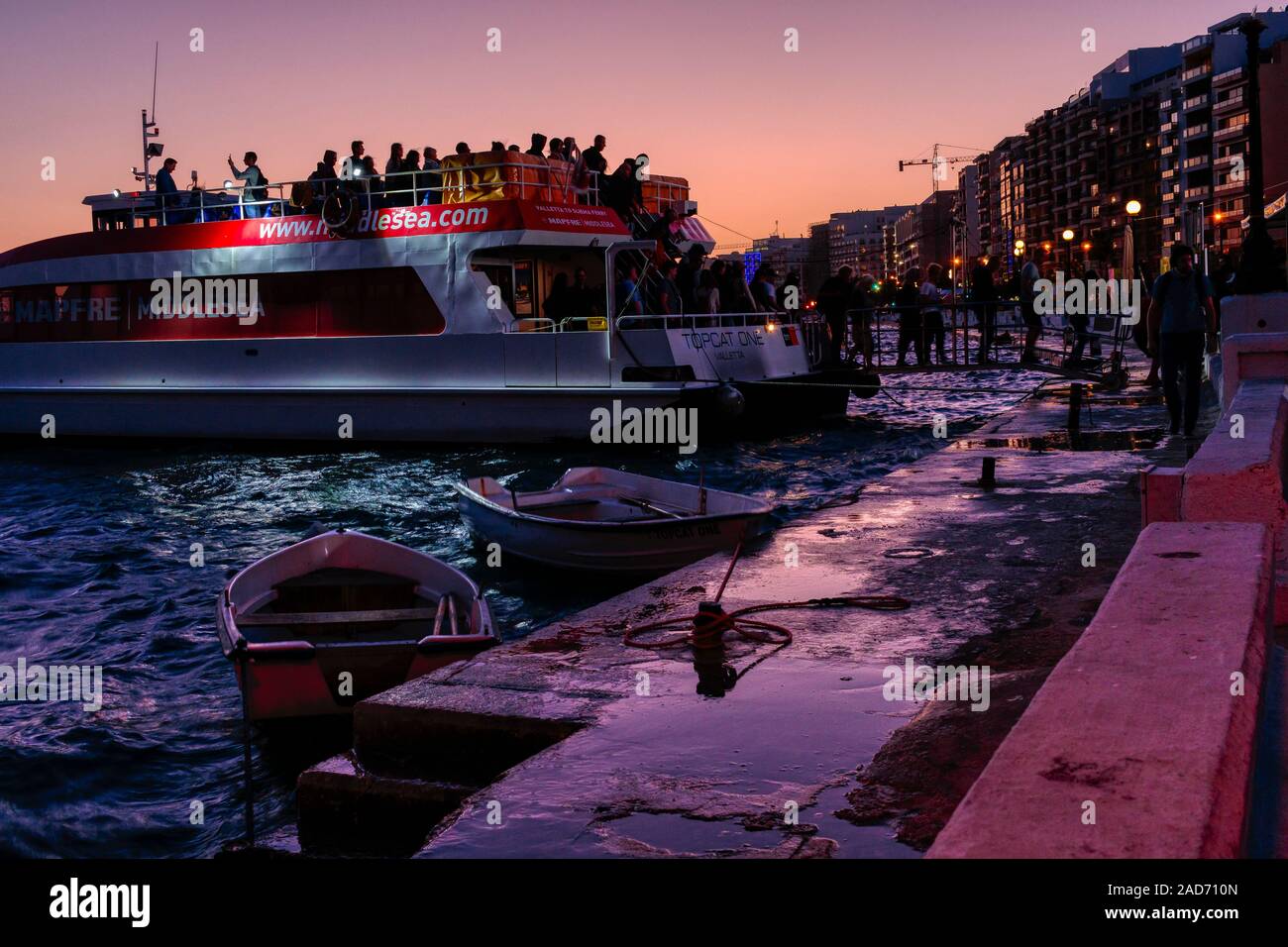The Topcat One Valletta water taxi disembarkation as it's visitors arrive in Sliema, Malta at sunset. Stock Photo