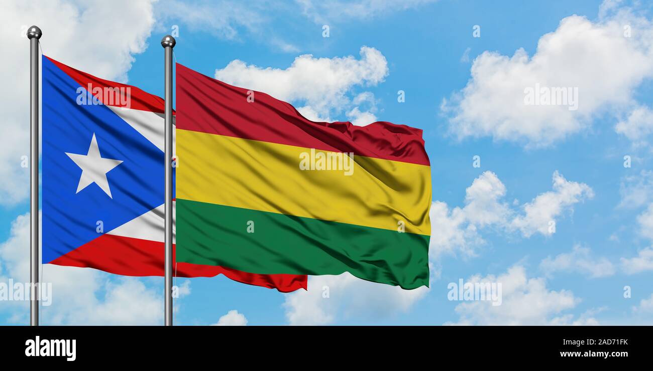 Puerto Rico and Bolivia flag waving in the wind against white cloudy blue sky together. Diplomacy concept, international relations. Stock Photo