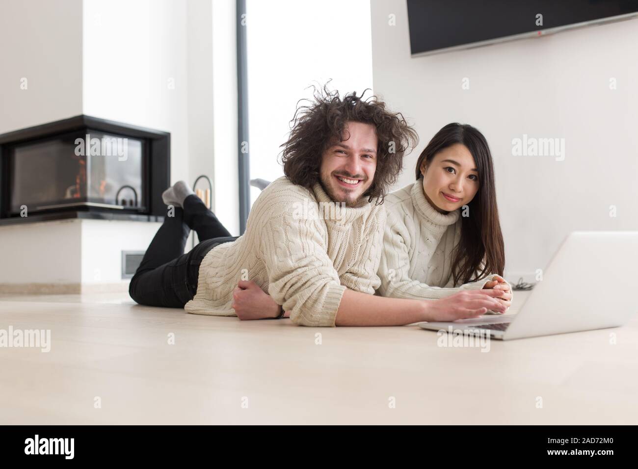 young multiethnic couple using a laptop on the floor Stock Photo
