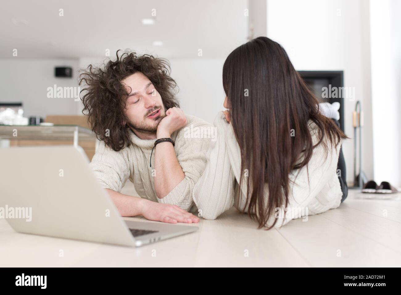 young multiethnic couple using a laptop on the floor Stock Photo