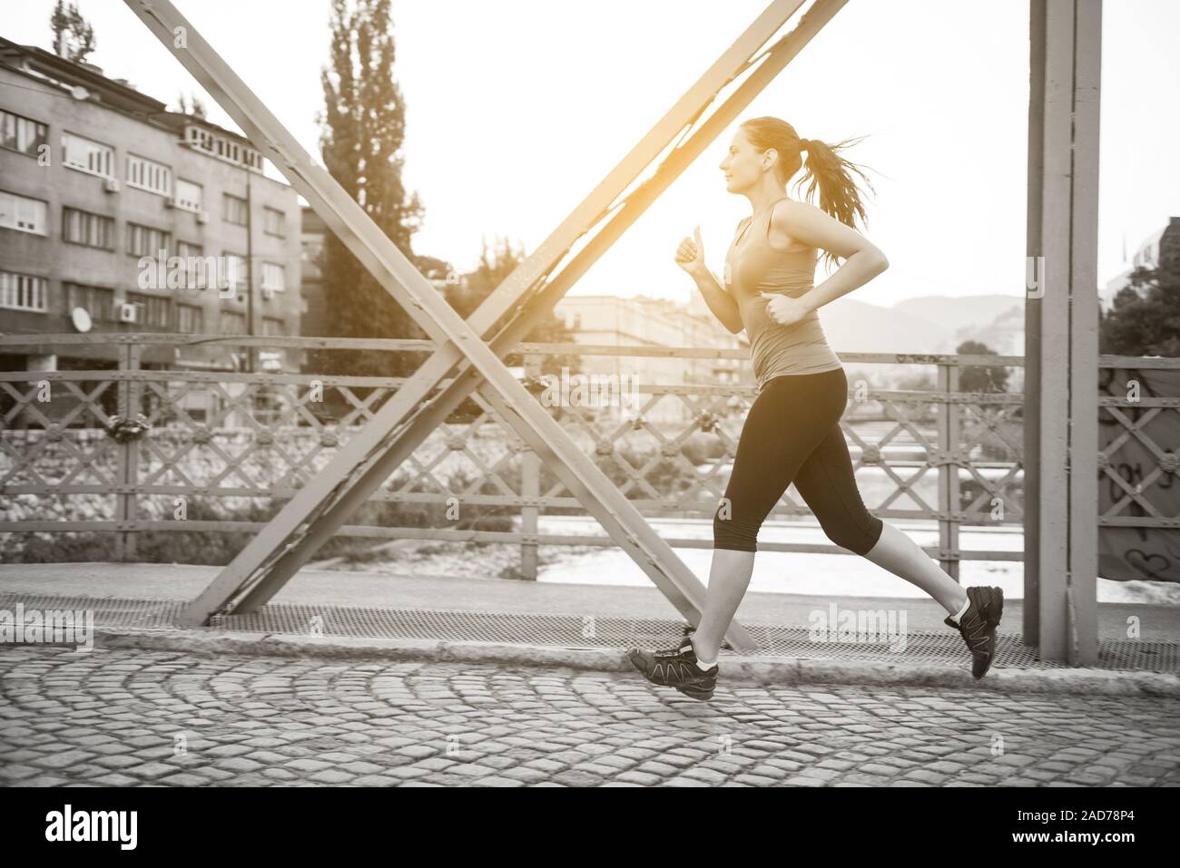 woman jogging across the bridge at sunny morning Stock Photo