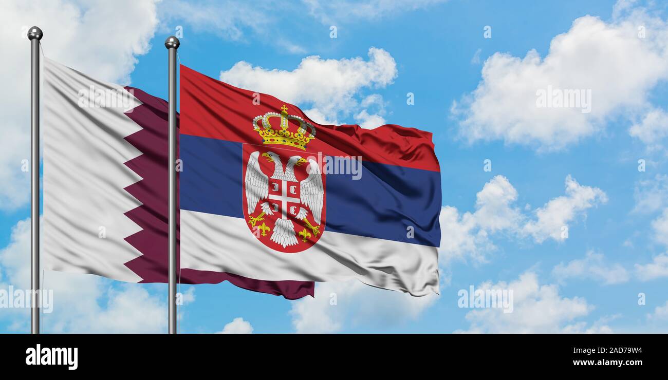 Qatar and Serbia flag waving in the wind against white cloudy blue sky together. Diplomacy concept, international relations. Stock Photo