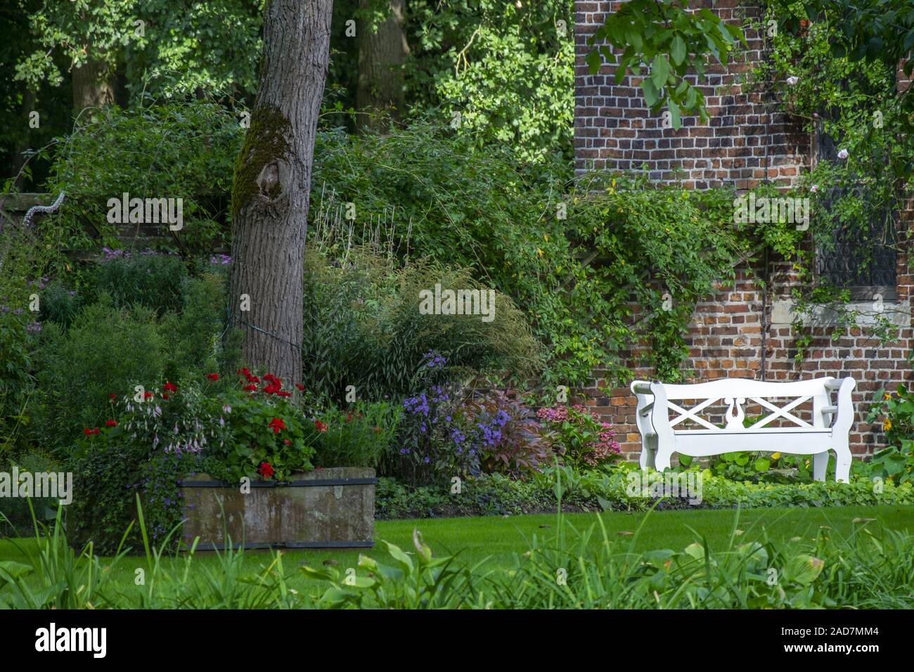 White garden bench in front of brick wall Stock Photo - Alamy