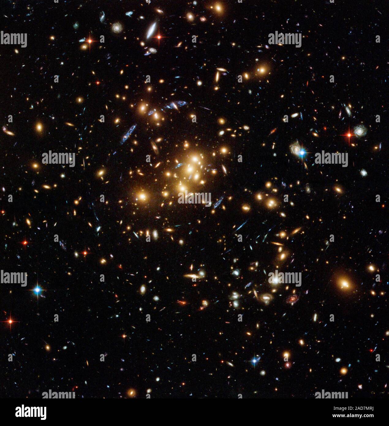 This rich galaxy cluster, catalogued as Cl 0024+17, is allowing astronomers to probe the distribution of dark matter in space. The blue streaks near the center of the image are the smeared images of very distant galaxies that are not part of the cluster. The distant galaxies appear distorted because their light is being bent and magnified by the powerful gravity of Cl 0024+17, an effect called gravitational lensing.   Dark matter cannot be seen because it does not shine or reflect light. Astronomers can only detect its influence by how its gravity affects light. By mapping the distorted light Stock Photo