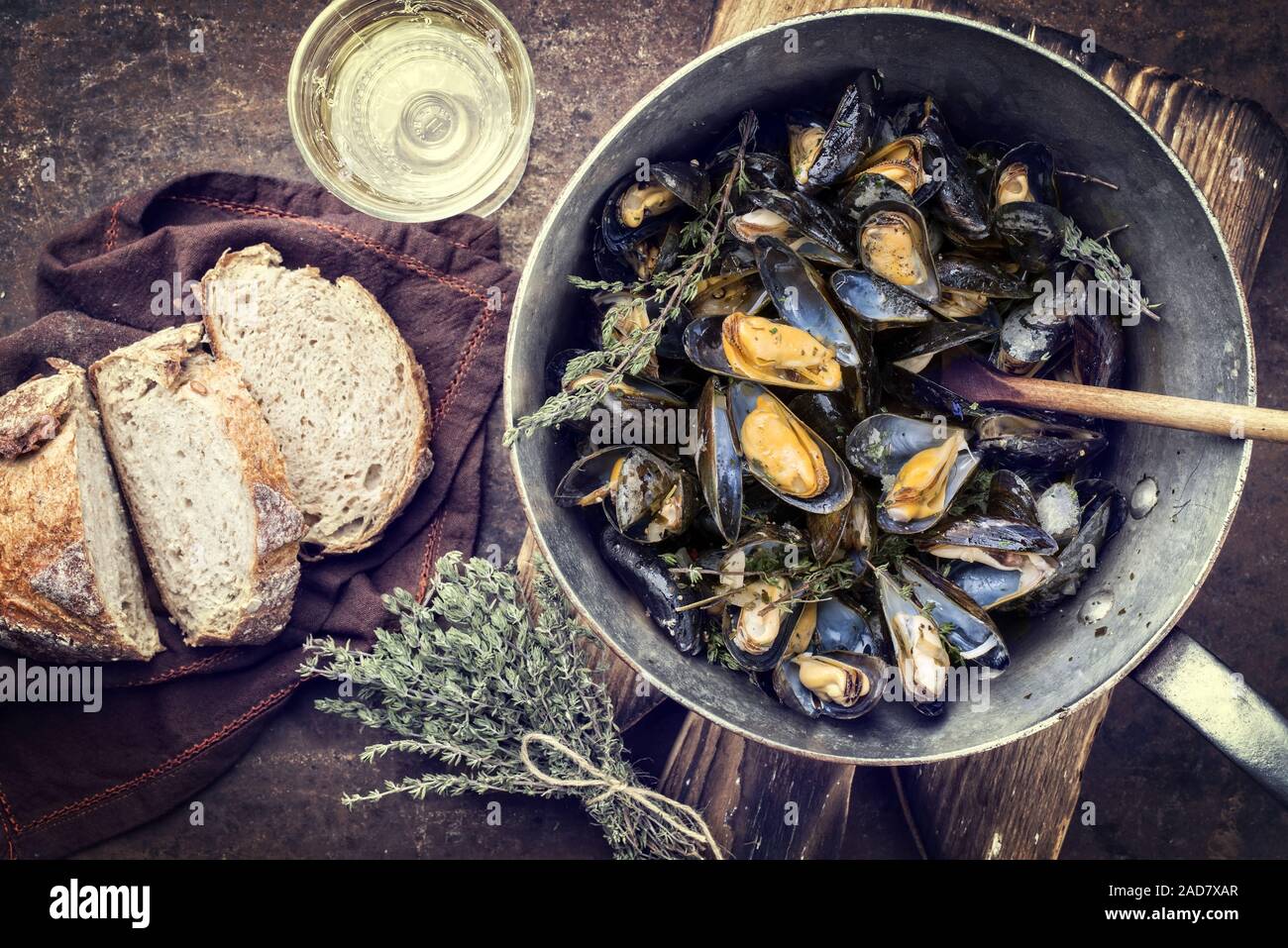 Traditional barbecue Italian blue mussel with farmhouse bread and white wine as top view in a casserole as vintage Stock Photo