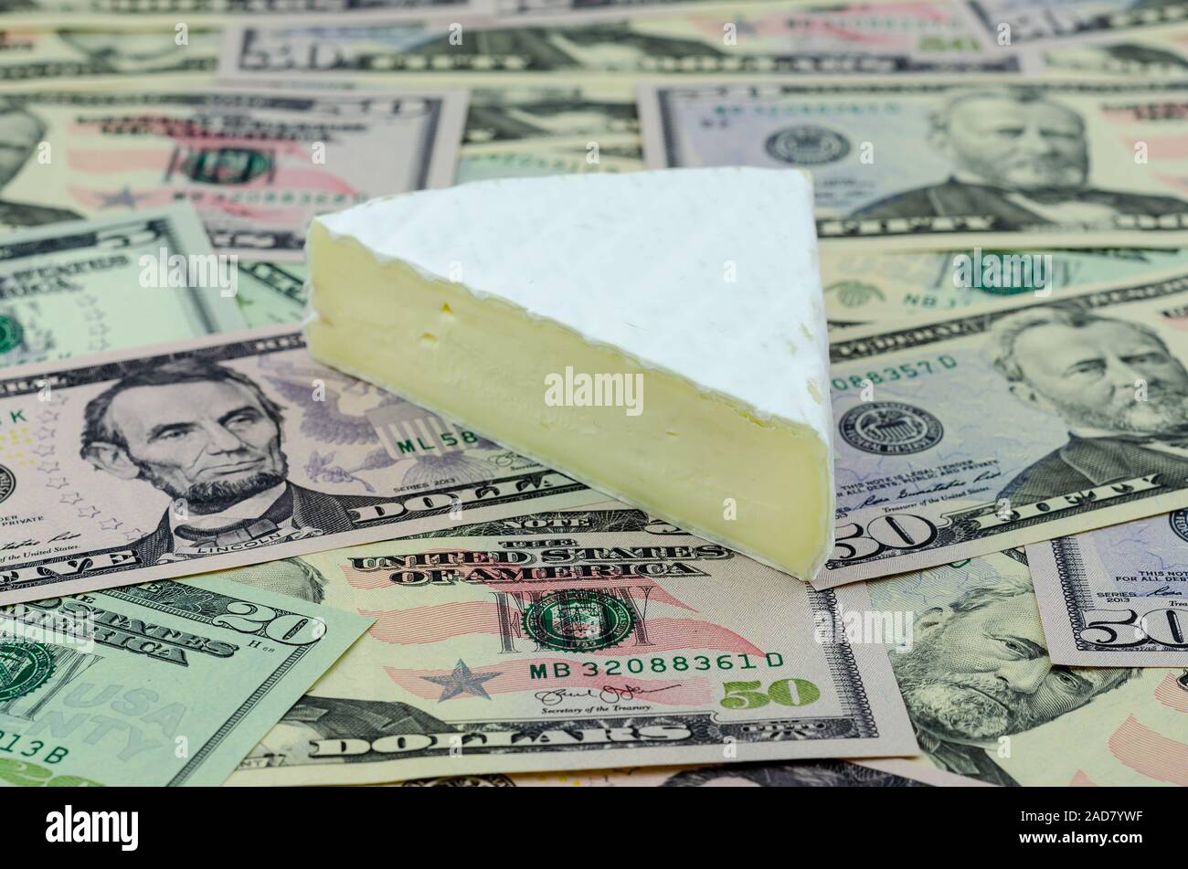 French cheese Brie on top of US dollar banknotes. Conceptual photo for US and France trade war and new  tariffs on imported cheese. Stock Photo