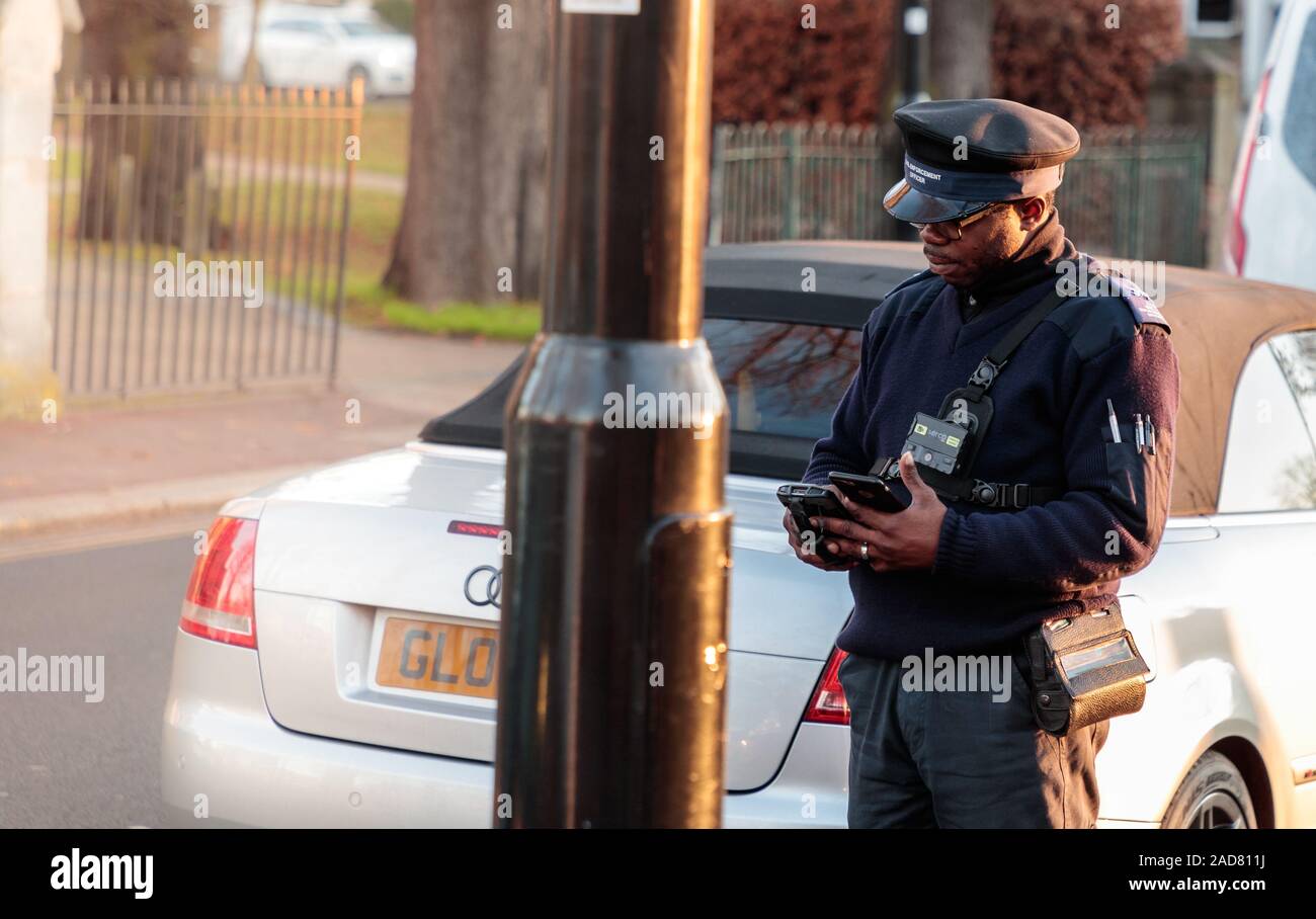 Traffic Warden writing/awarding a parking ticket (PCN) in Chiswick, London, UK Stock Photo