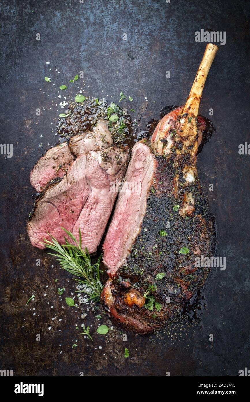Traditional barbecue leg of lamb sliced with spice and herb as top view on a metal sheet Stock