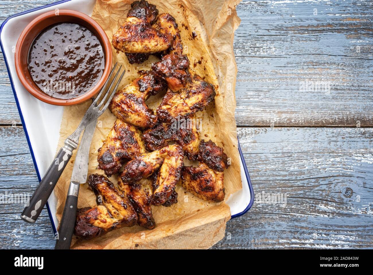 Traditional barbecue chicken wings with hot chili sauce as top view in a skillet with copy space