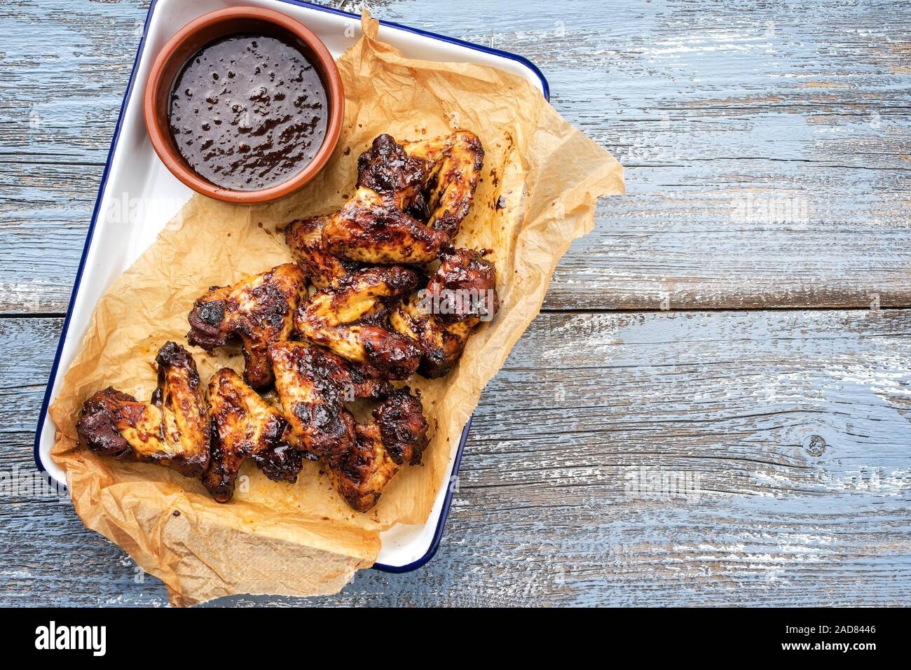 Traditional barbecue chicken wings with hot chili sauce as top view in a skillet with copy space