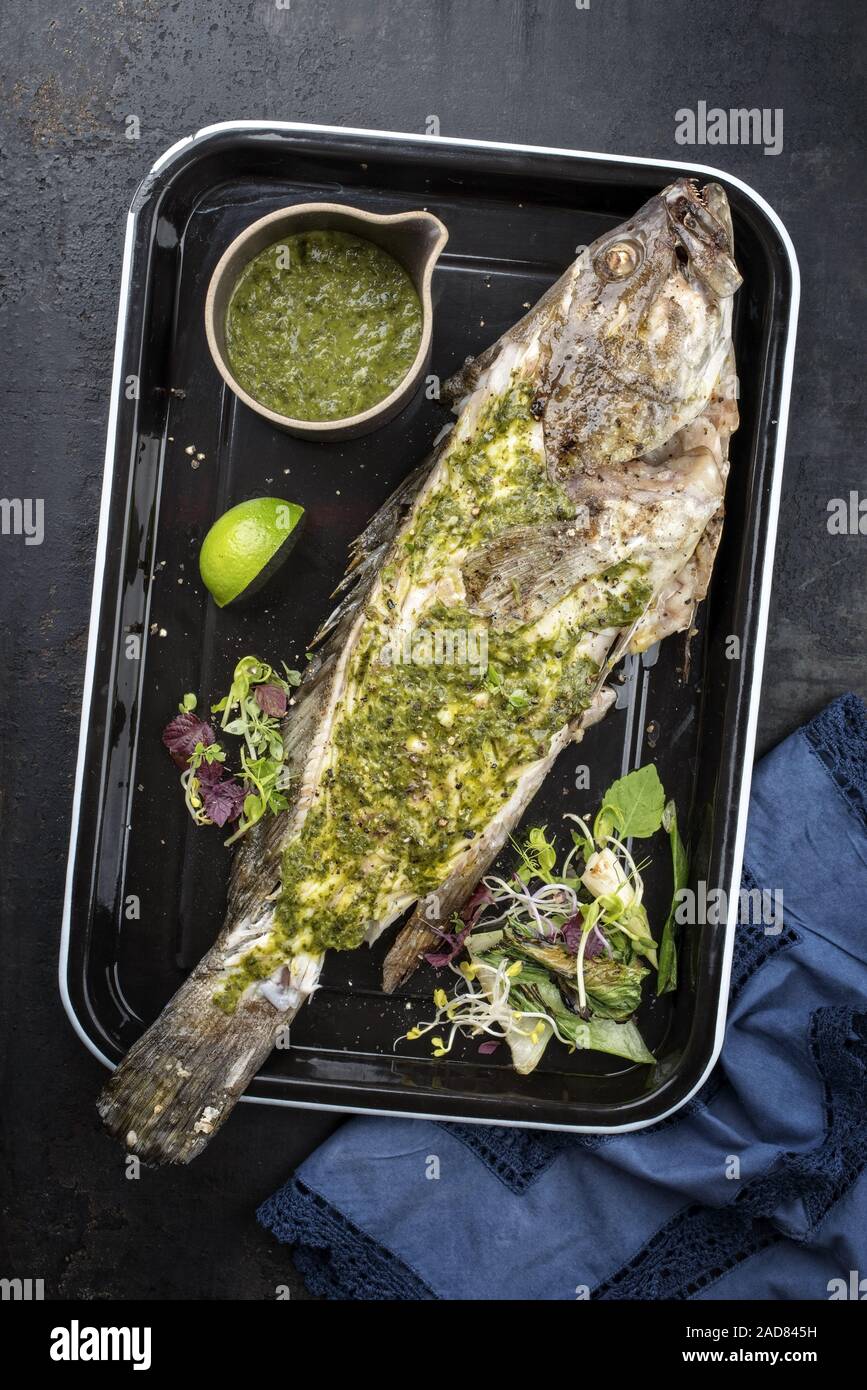 Barbecue white grouper with chimichurri sauce aji criollo as top view in a black skillet Stock Photo