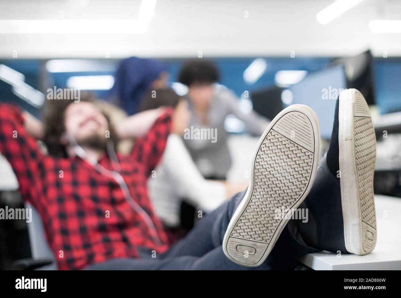 software developer resting with legs on desk Stock Photo