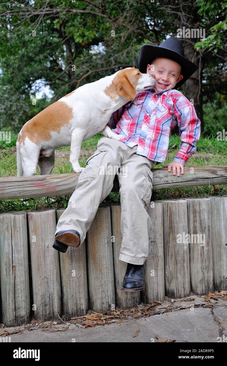 Boy wearing cowboy hat and boots with pet dog Beagle Stock Photo