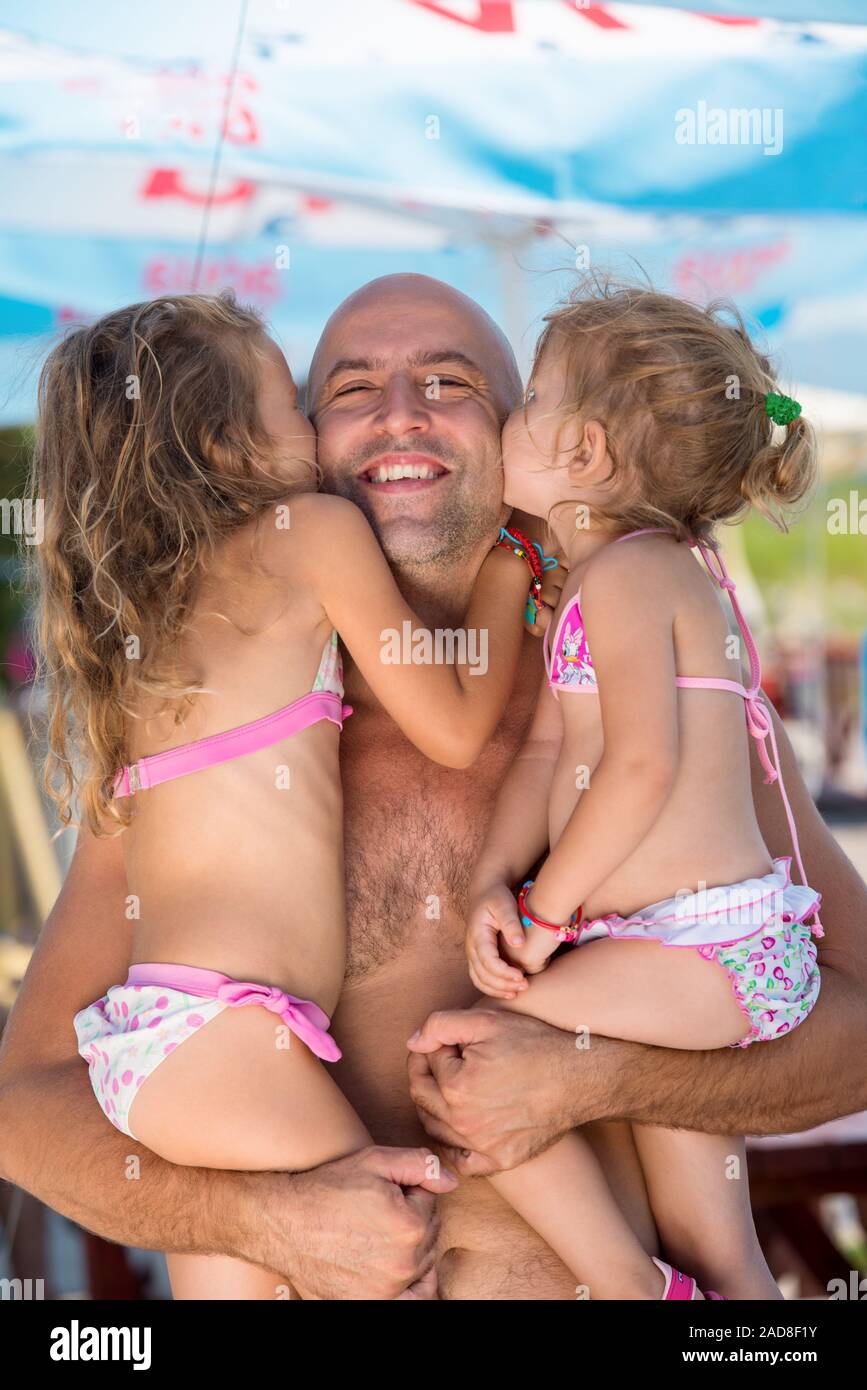 portrait of young happy father with daughters by the sea Stock Photo