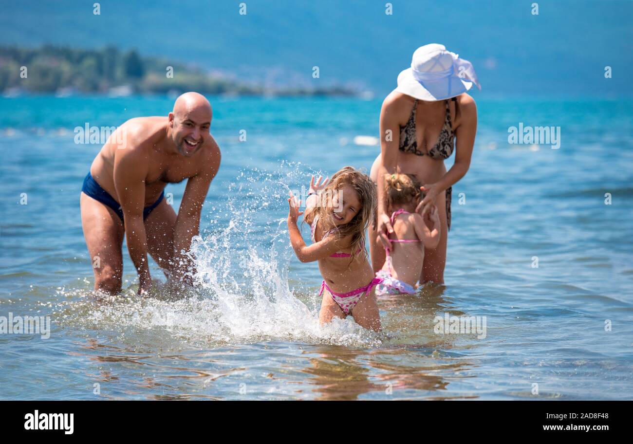 happy family splashing each other at beach Stock Photo