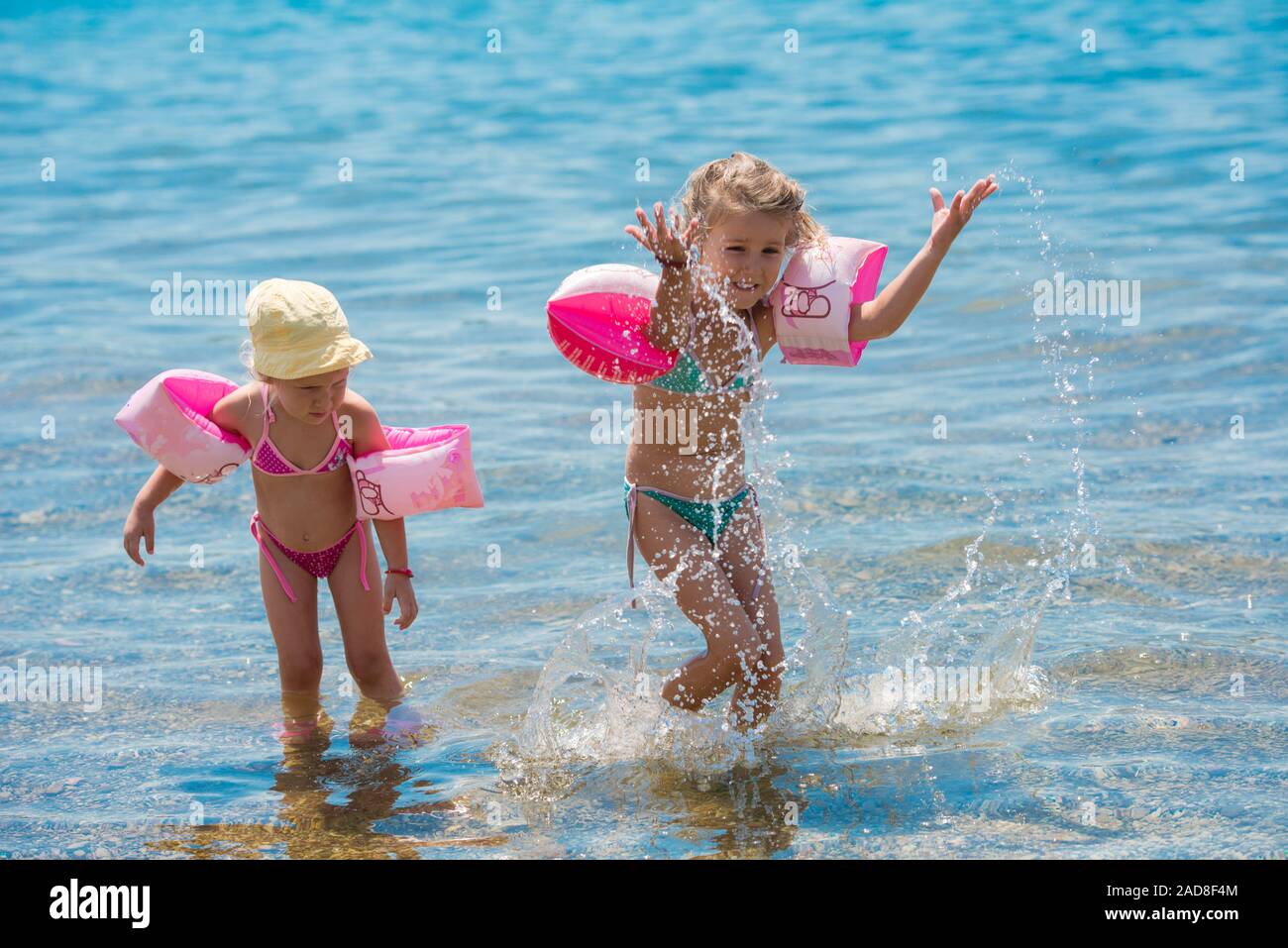 little girls with swimming armbands playing in shallow water Stock Photo